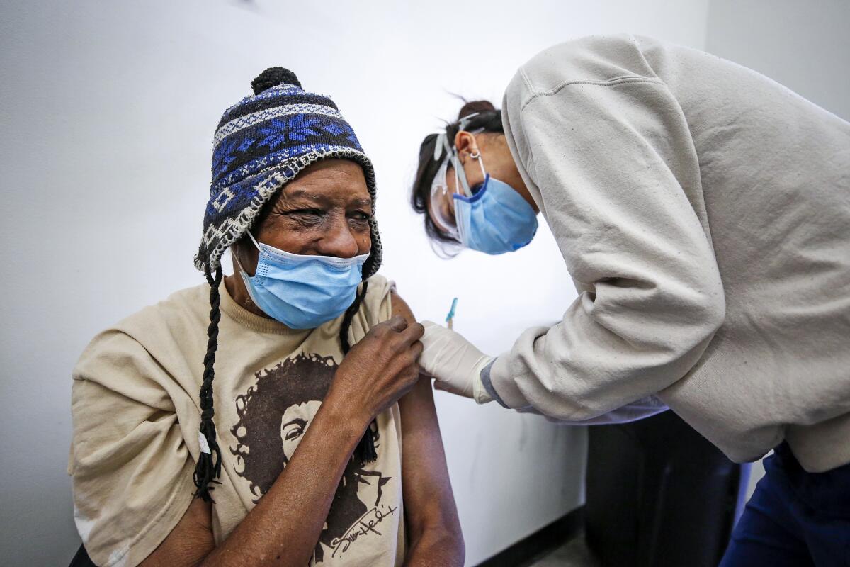 Registered nurse Katherine Han delivers a COVID-19 vaccination to Lance Curtis, 65, in downtown L.A.'s skid row on Feb. 5.