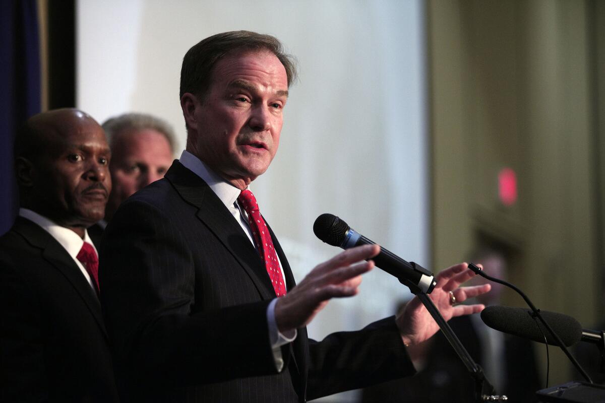 Michigan Atty. Gen. Bill Schuette, shown announcing 13 felony charges against officials on April 20, says he is suing two companies over Flint's lead-tainted water crisis.