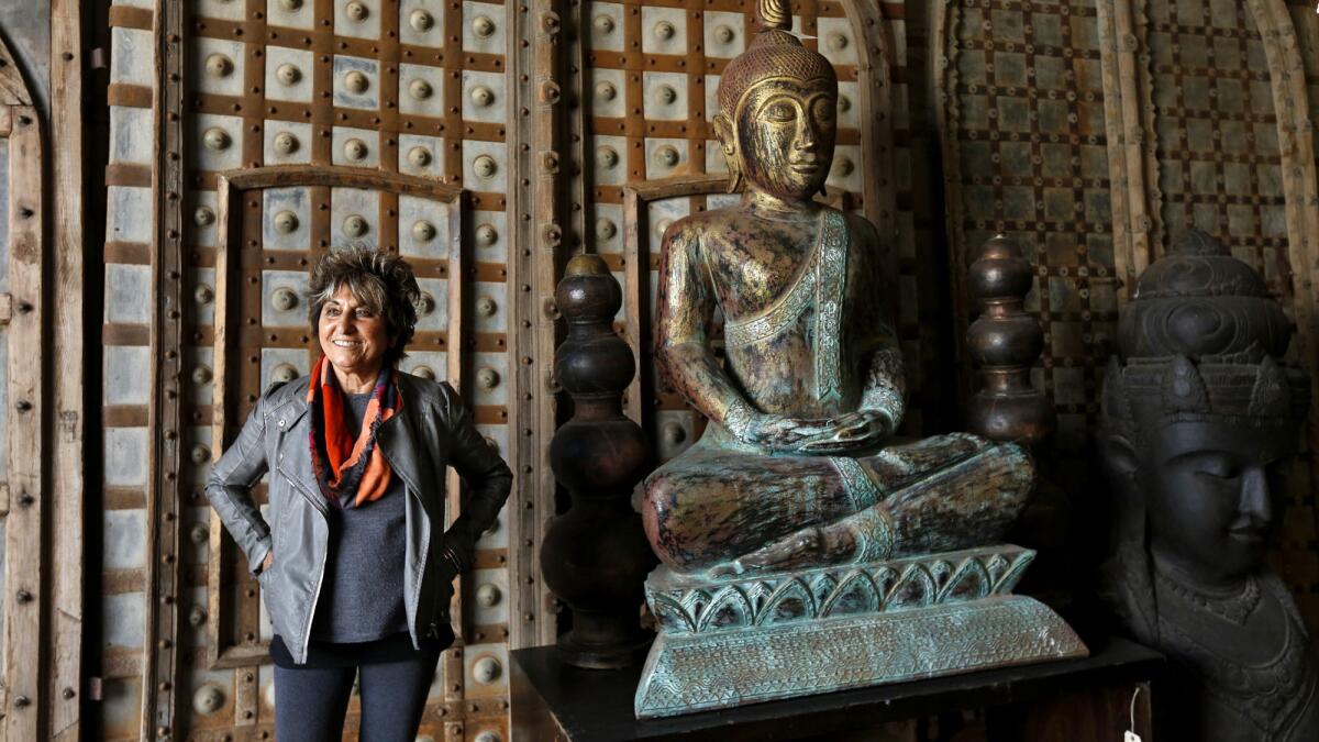 Suad Cano, owner of Berbere World Imports, next to antique doors from India and a Buddha from Indonesia.