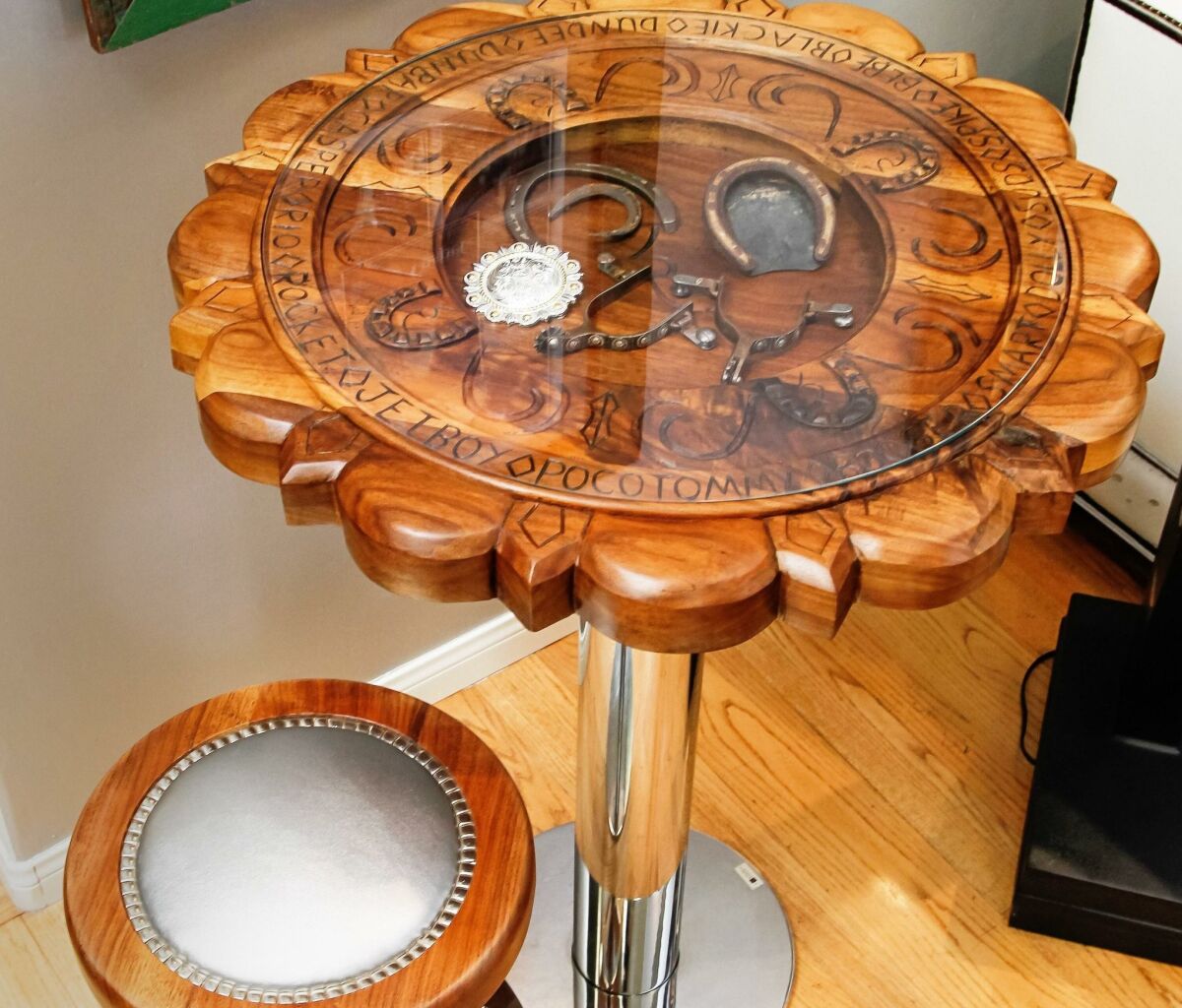 Holmquist’s Concho hand-carved table and stool displays names of horses the family has owned. — Eduardo Contreras