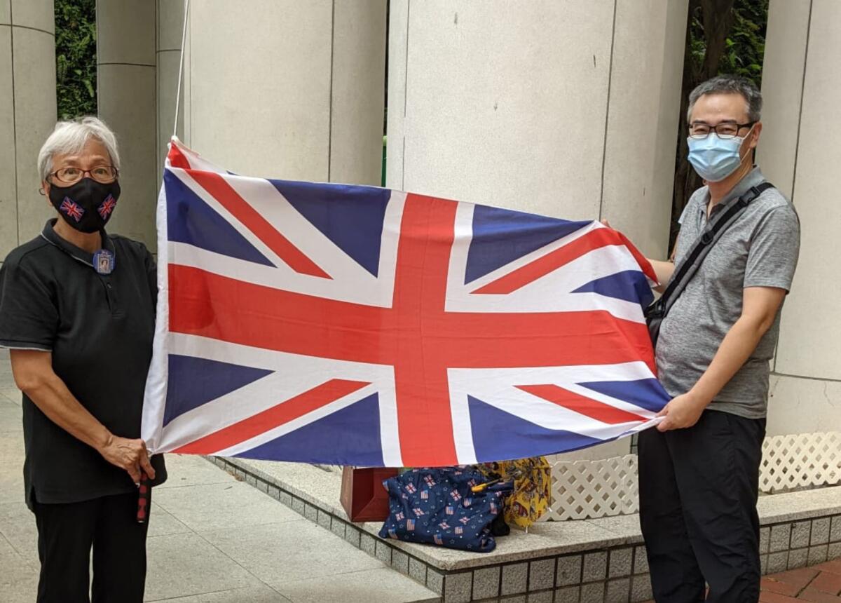 A woman and a man wearing masks hold up the United Kingdom flag.
