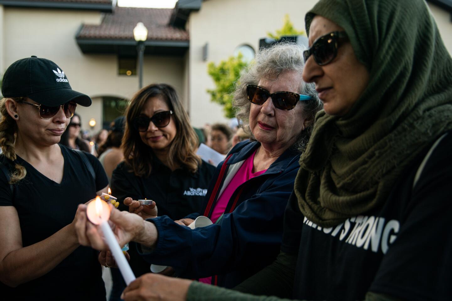 Gilroy residents light candles together during a vigil at Gilroy City Hall on Monday. (Kent Nishimura / Los Angeles Times)