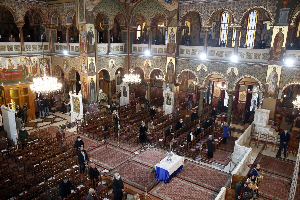 A limited congregation attends the service for the feast of the Epiphany in the Church of the Holy Trinity in Piraeus, the port of Athens, Wednesday, Jan. 6, 2021. The Greek government relented and allowed limited attendance at churches celebrating the feast of the Epiphany on Wednesday, reversing a ban on attendance designed to limit the spread of the coronavirus. (AP Photo/Thanassis Stavrakis)