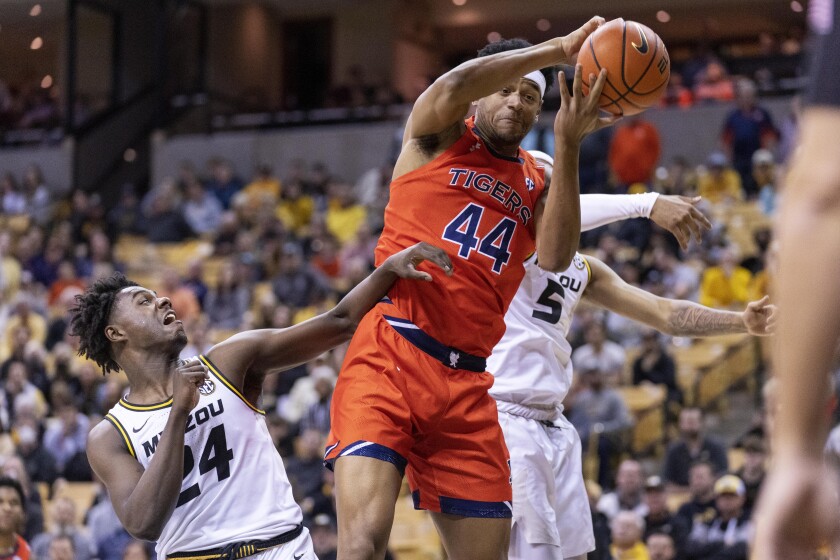 Auburn's Dylan Cardwell, center, pulls down a rebound in front of Missouri's Kobe Brown, left, and Jarron Coleman, right, during the first half of an NCAA college basketball game Tuesday, Jan. 25, 2022, in Columbia, Mo. (AP Photo/L.G. Patterson)