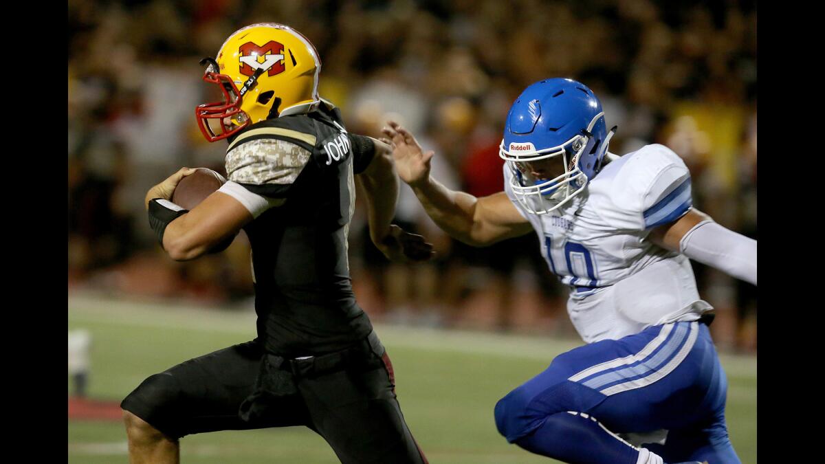 Mission Viejo quarterback Brock Johnson eludes the grasp of Norco linebacker Victor Viramomtes for a long gain in the first quarter Friday.