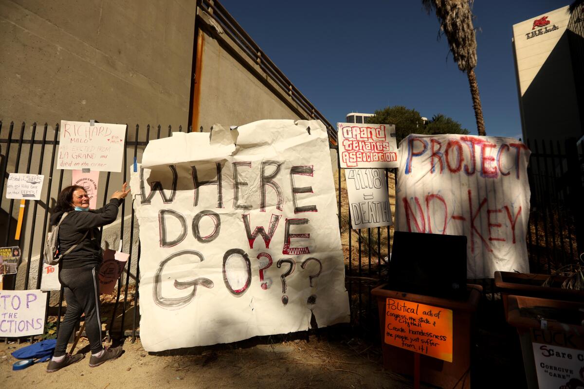 A woman stands next to a banner reading "Where do we go?"