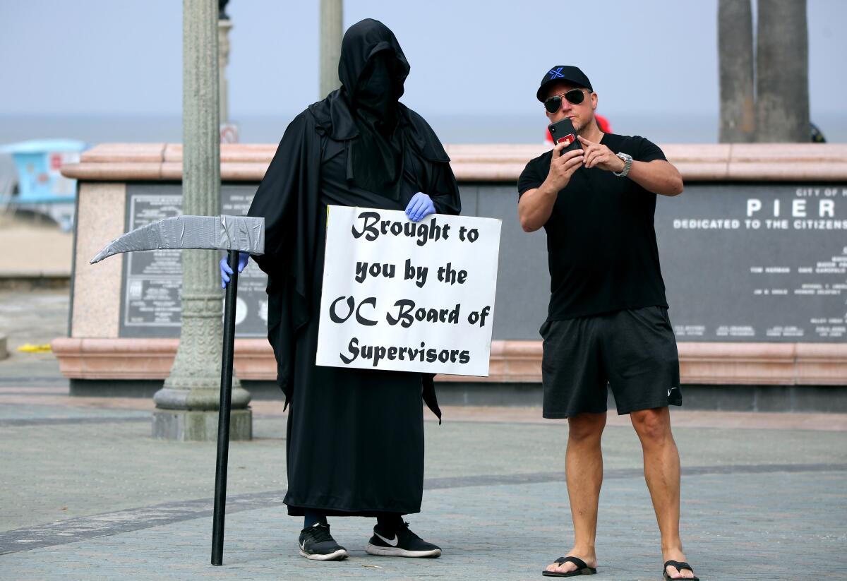 Tomas, right, who declined to give his last name, takes a selfie with the Grim Reaper, also known as Spencer Kelly from Huntington Beach, on Friday.