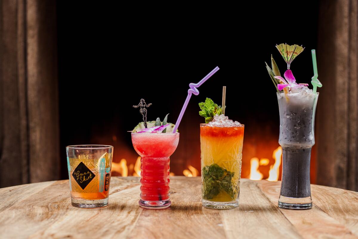 A line of four cocktails on a wood table at the Grass Skirt.