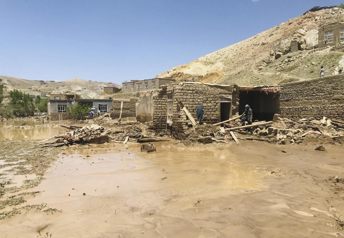 Afghan men collects their belongings from a home damaged in flooding. 