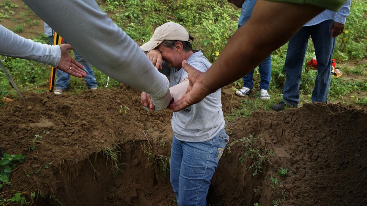 Rosalia Castro, 61, whose son disappeared in 2011, is overcome with emotion while helping to excavate a clandestine grave.