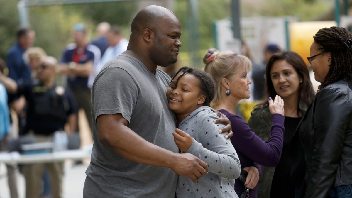 Fifth-grader Myla Grissom, 11, receives a hug from her father, Calvin Grissom, at the evacuation release point at Castle View Park in Riverside.