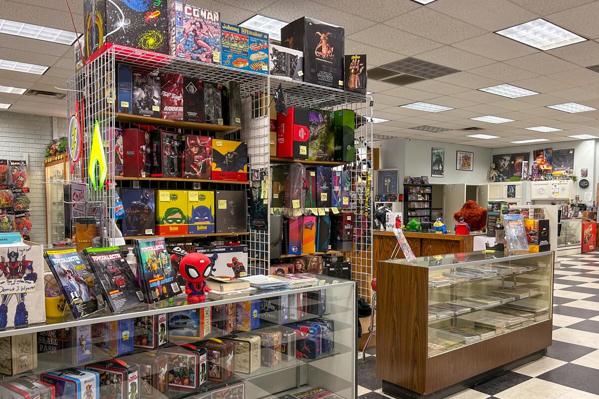 A store interior with display cases and shelves filed with merchandise related to comics, movies and games