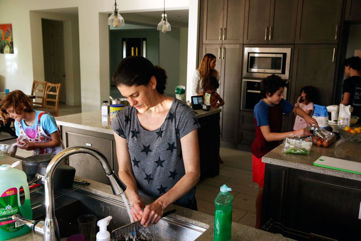 The Levinson and Knight families cook together in their shared home.