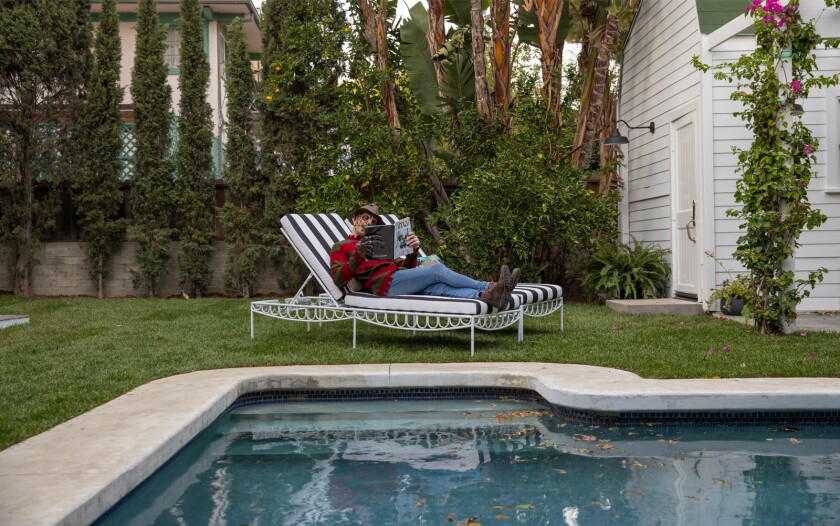 A man dressed as Freddy Krueger sits next to a swimming pool.