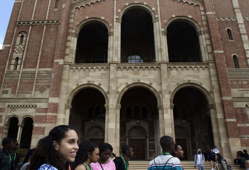 Prospective students walk past a building with tall archways at UCLA.
