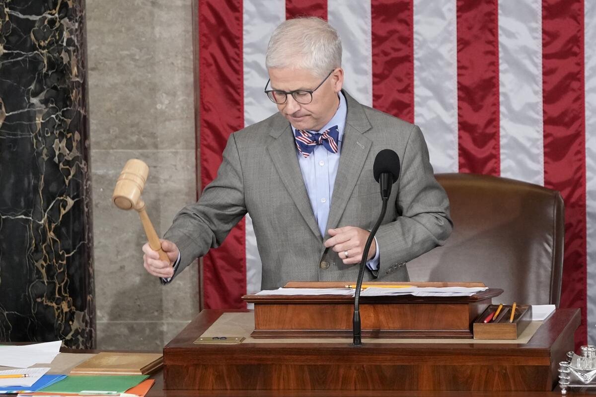 A man lifting a gavel and standing in front of an American flag.