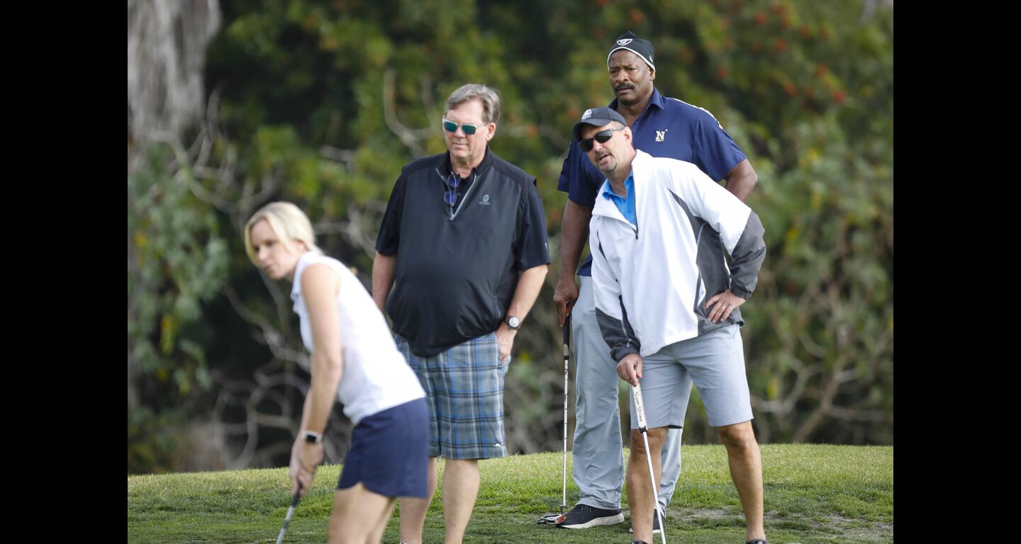 Napoleon McCallum who played football for the U.S.Naval Academy and Oakland Raiders, right, looks on with other players, Ken Sayer and Rick Doubleday, as Laura Enders tees off during the Navy-Notre Dame Golf Tournament at the Riverwalk Golf Club in Mission Valley in advance of the football game between the two schools to be held at SDCCU Stadium, Saturday.