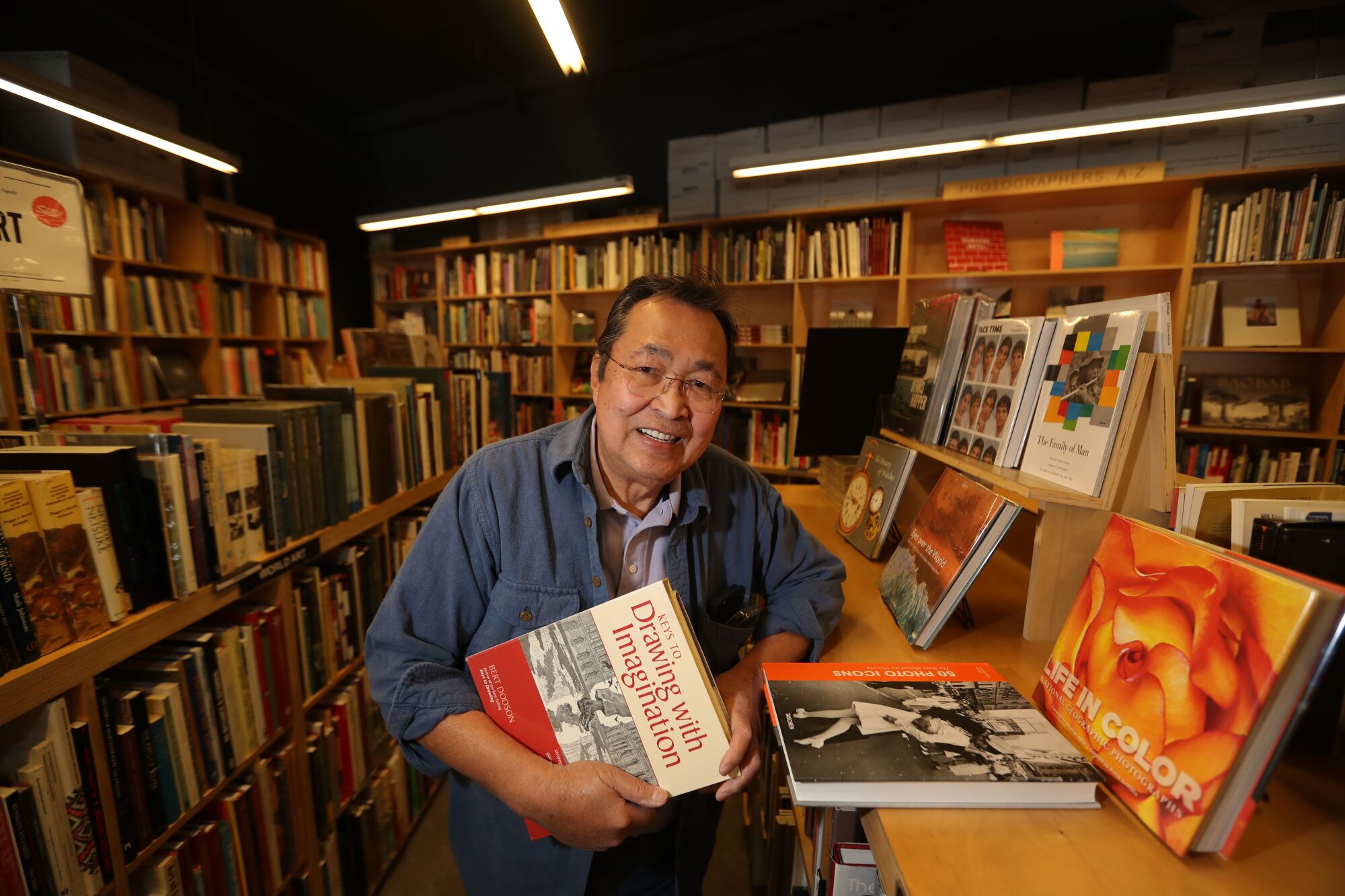 A man holds a book called "Keys to Drawing With Imagination."