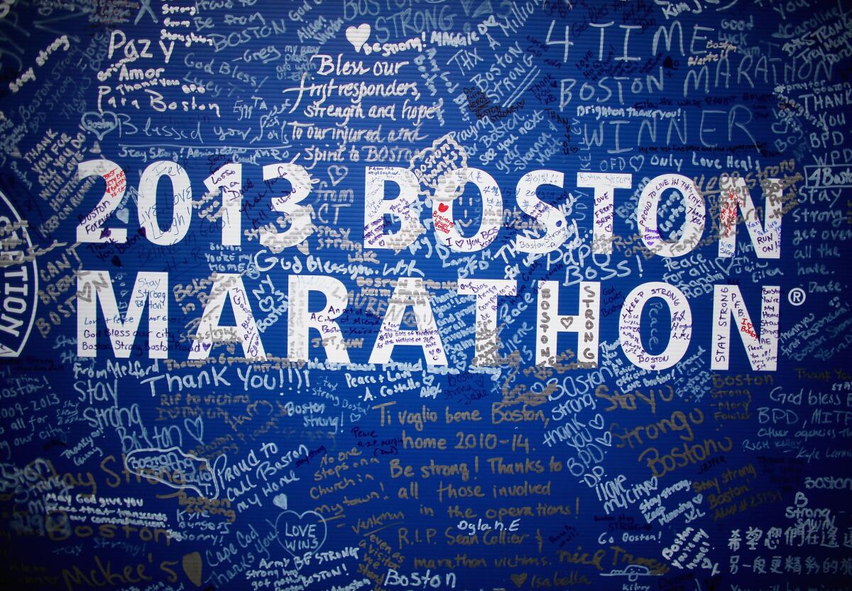 Signatures adorn a Boston Marathon poster near the site of the bombings on Boylston Street. The street fully reopened Wednesday.