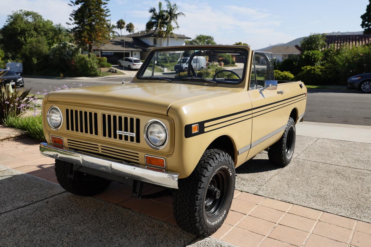 A yellow, topless International Harvester Scout II parked in a sunny driveway