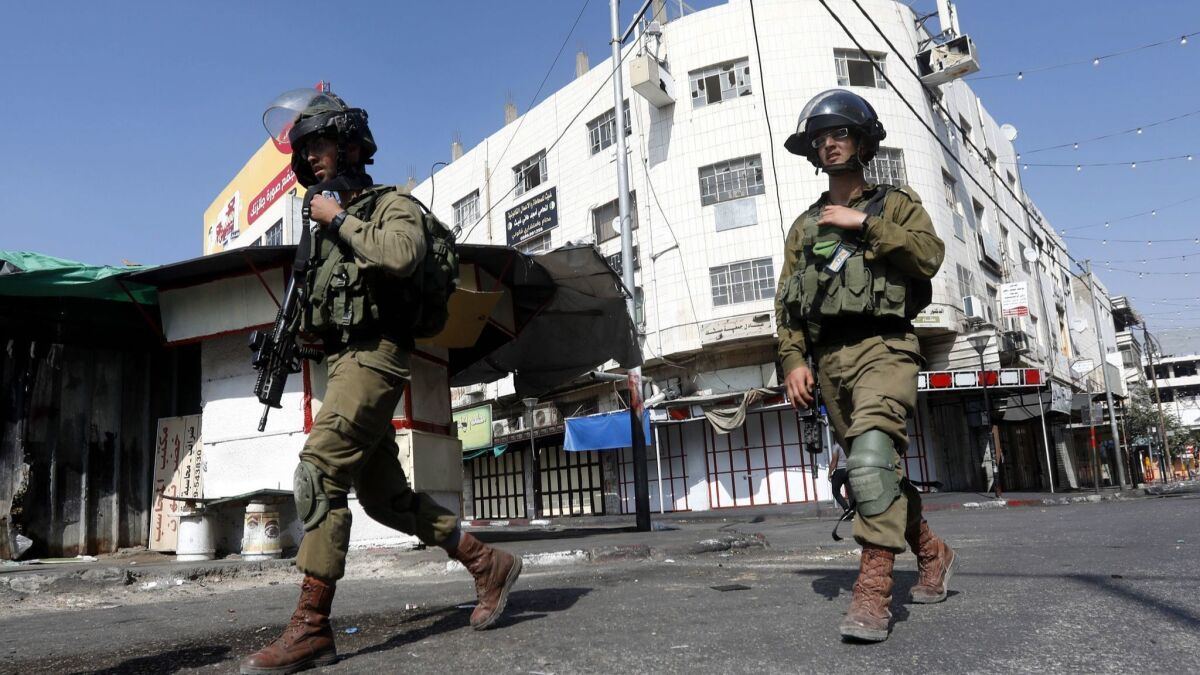 Israeli army soldiers take position during clashes with Palestinian stone throwers in the West Bank city of Hebron on August 3.