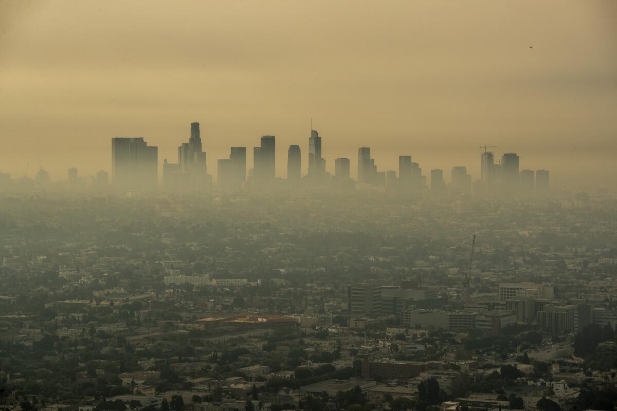 Smoke from Southern California wildfires drifts through the L.A. Basin, obscuring downtown skyscrapers in the distance.