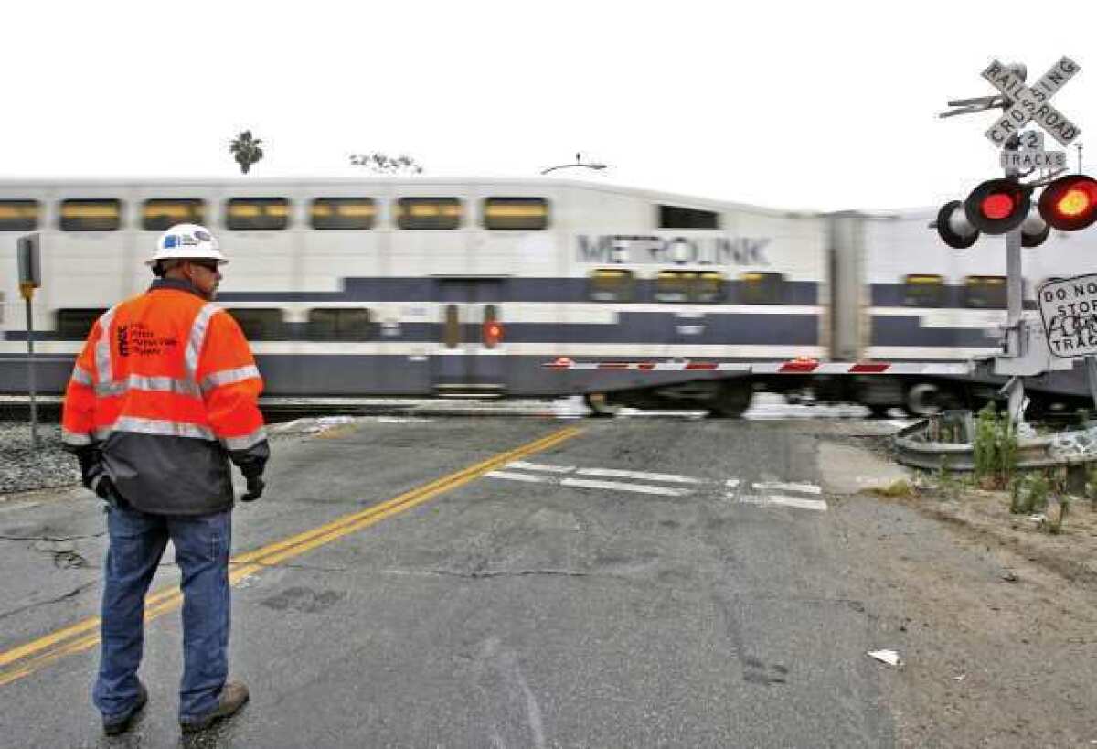 A Metrolink employee keeps an eye on traffic as a train passes by the Doran Street and San Fernando Road crossing in Glendale.