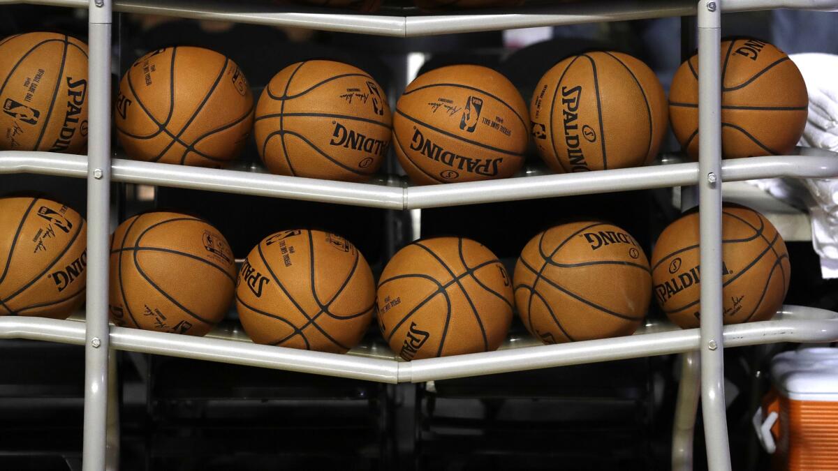 Basketballs sit in a rack on the court 