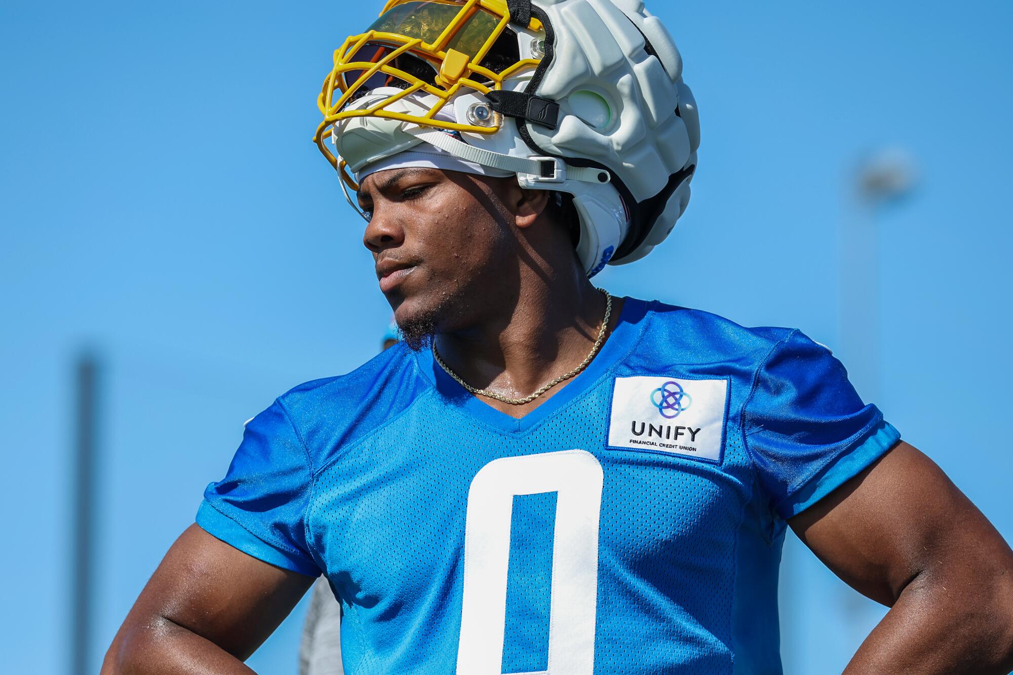 Chargers rookie Daiyan Henley stands at practice with his helmet on top of his head.