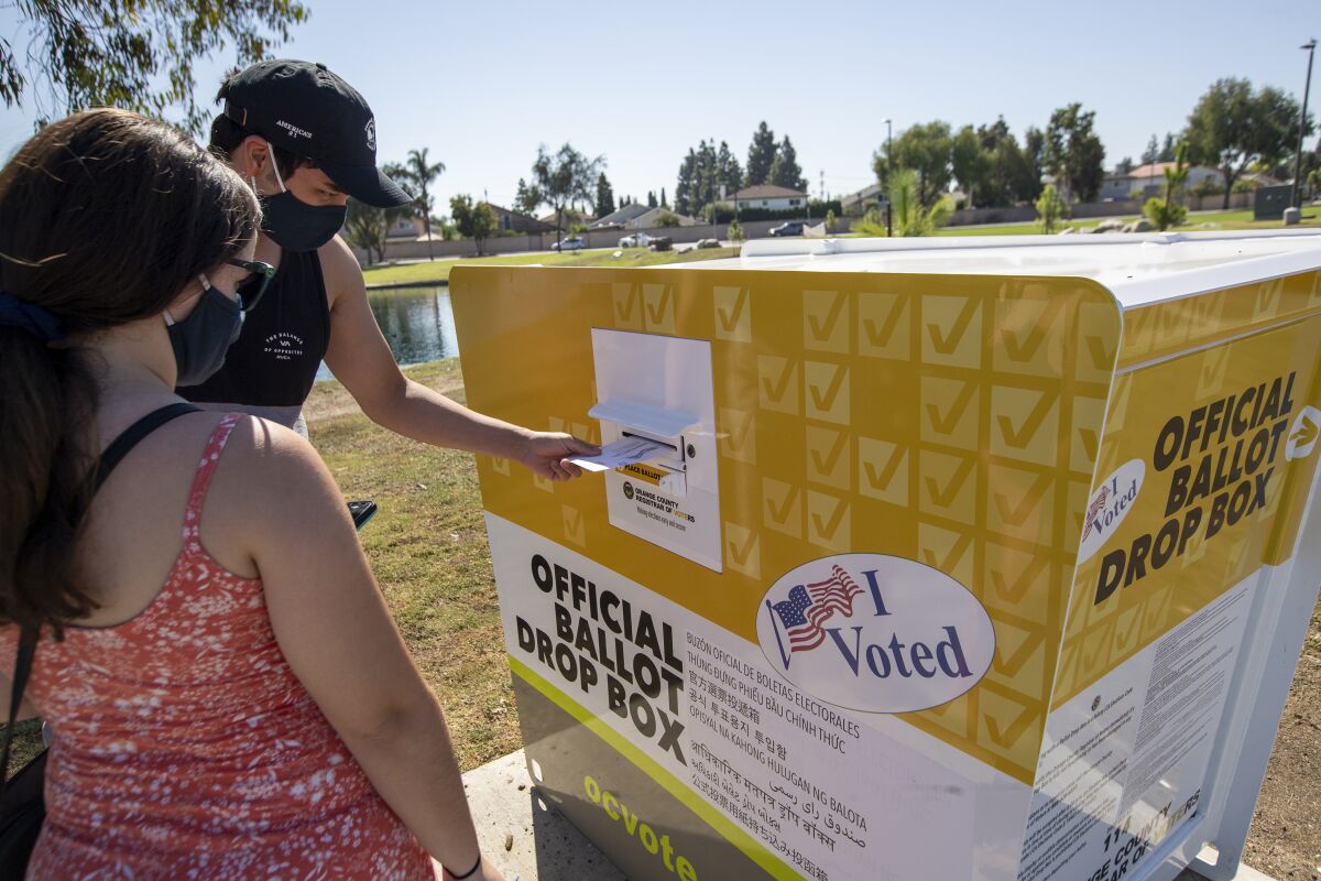 Voters place their ballots in an official ballot drop box.
