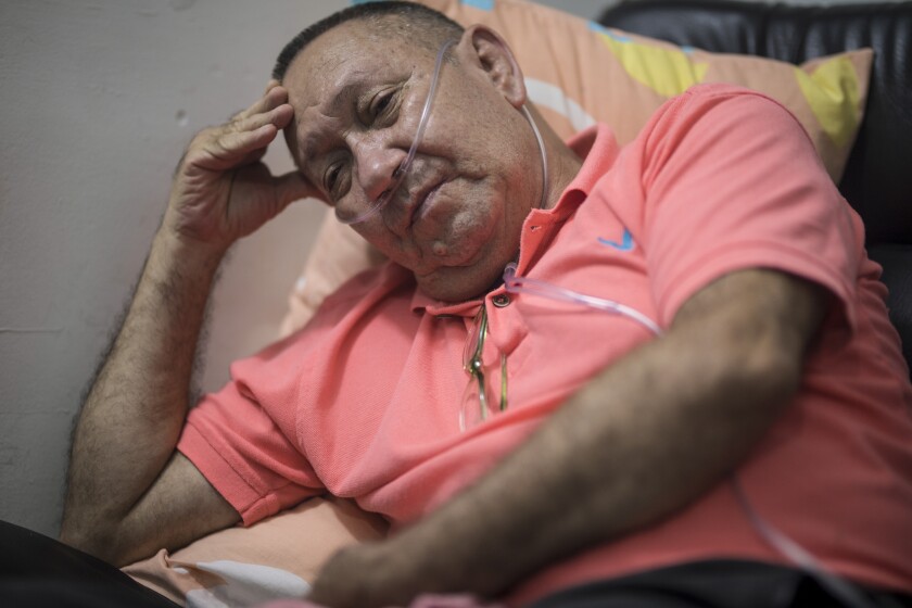 Victor Escobar sits at his home during an interview in Cali, Colombia, Thursday, Jan. 6, 2022. Escobar, who suffers chronic obstructive pulmonary disease, oxygen dependence, lack of muscle control and secondary effects from a stroke is scheduled on the evening of Jan. 7 to become the first person to receive euthanasia legally, without being a terminally ill patient. Euthanasia for terminally ill patients is legal in Colombia. (AP Photo/Ivan Valencia)