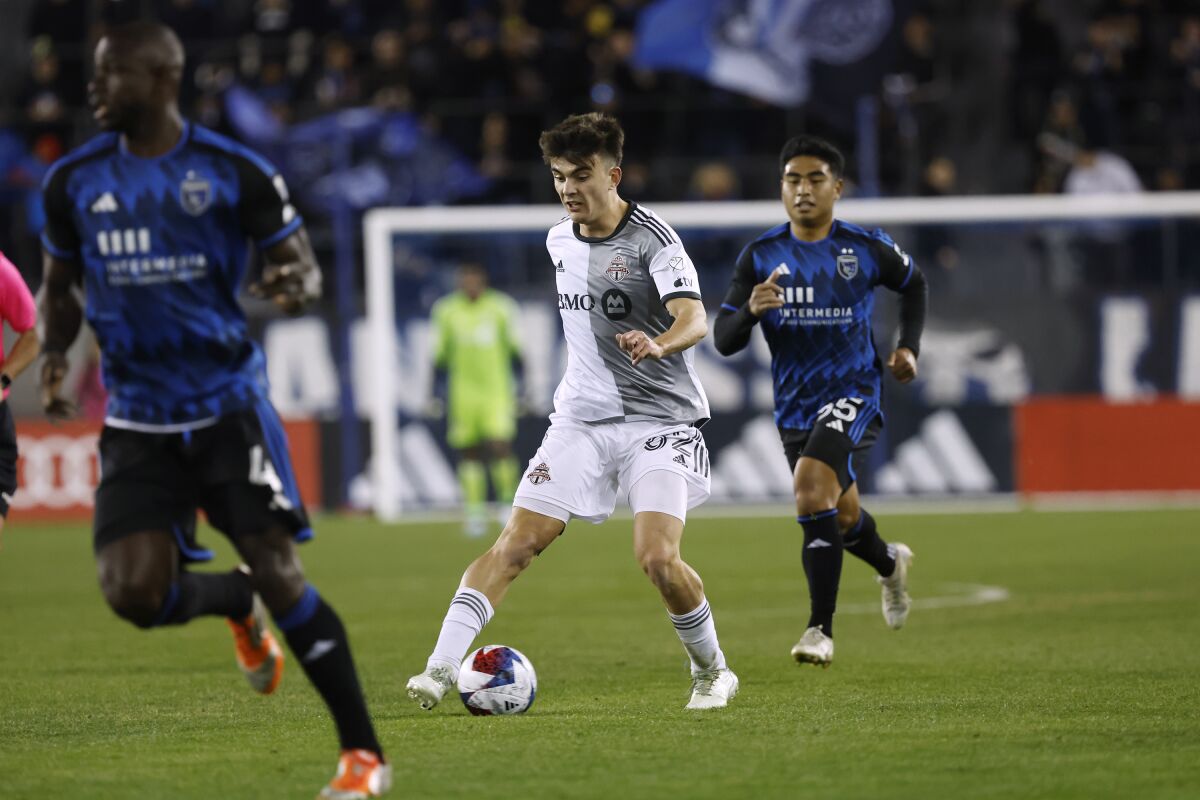 Toronto FC midfielder Alonso Coello, center, brings the ball up the field in front of San Jose Earthquakes midfielder Michael Baldisimo, right, during the second half of an MLS soccer match in San Jose, Calif., Saturday, March 25, 2023. (AP Photo/Josie Lepe)