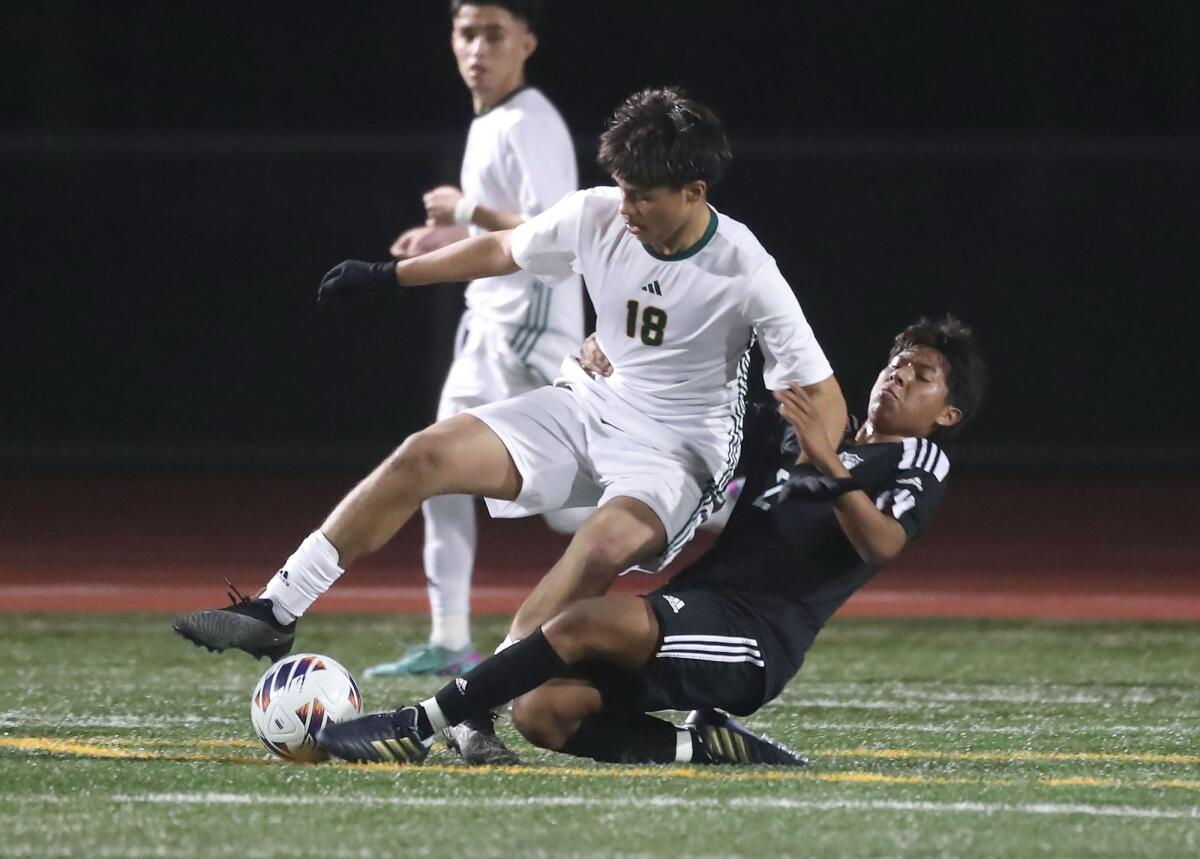 Costa Mesa's Christian Garcia (2) tackles Saddleback's Giovanni Tamayo (18) as the pair battle for the ball at midfield.