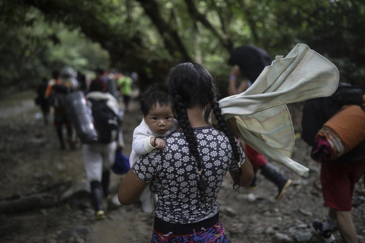 Una migrante boliviana carga un bebé mientras cruza el Tapón del Darién, de Colombia a Panamá,