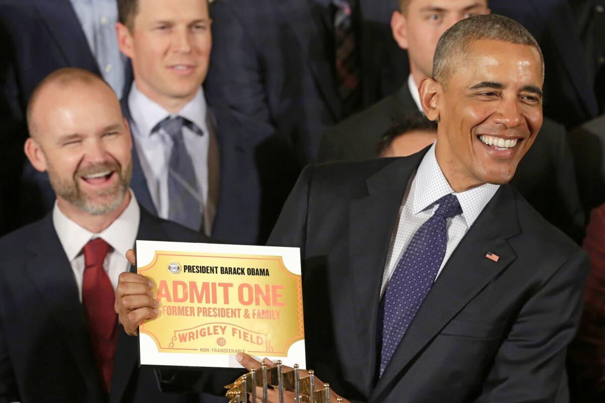 President Obama holds a lifetime admission certificate to Wrigley Field at a White House event honoring the World Series champion Chicago Cubs.
