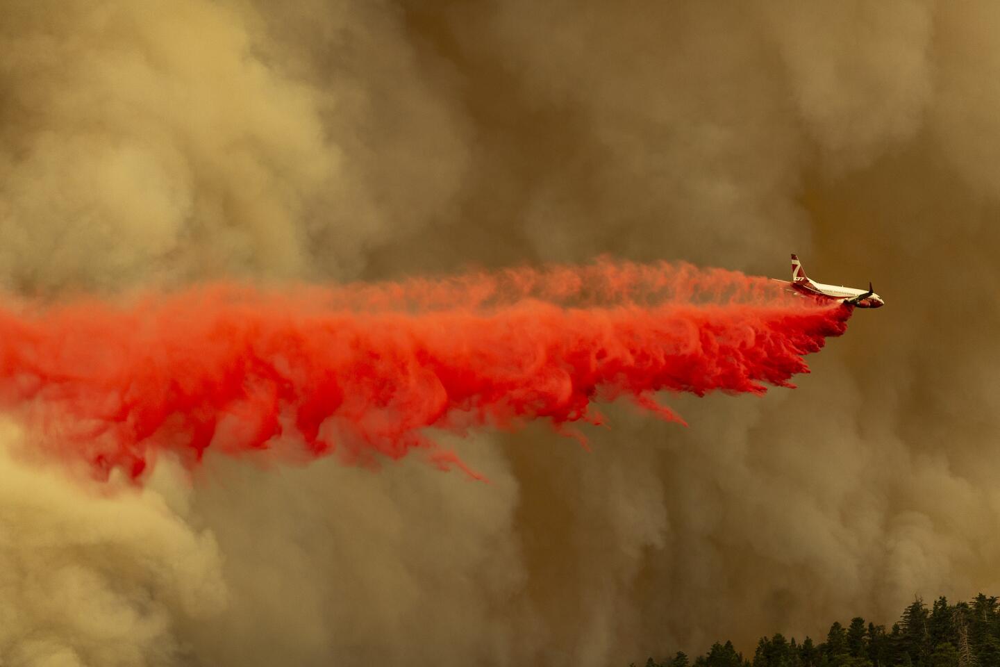 A Coulson 737 firefighting tanker jet drops fire retardant to slow the fire.