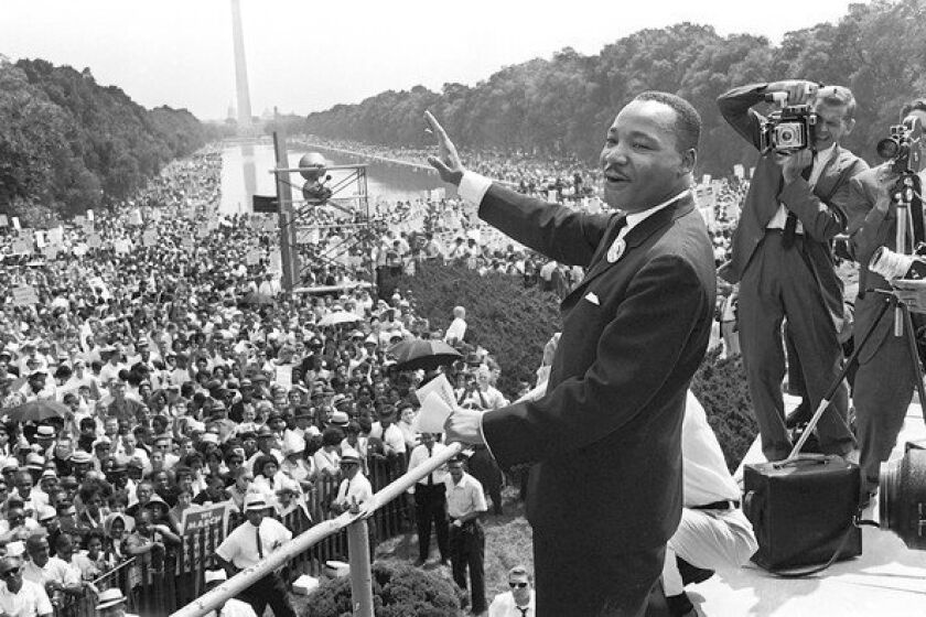 The Rev. Martin Luther King Jr., center, waves from the steps of the Lincoln Memorial to supporters on the Mall in Washington, D.C., on Aug. 28, 1963.