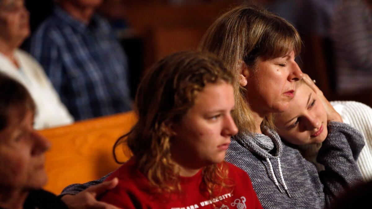 Teresa Gathman holds her daughters Gianna, 18, in red, and Gabriella, 15, during Mass at St. Rose Catholic Church in Santa Rosa. The family lost their Fountaingrove house to the fire and moved in with Teresa's parents.