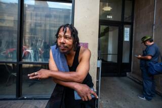 Los Angeles, CA - August 30: Solomon Mustaffa, 48, stands outside the Hotel Alexandria located at West 5th Street and South Spring Street on Wednesday, Aug. 30, 2023, in Los Angeles, CA. He says he has lived in this building for about six years. About 30 yards away a coalition of homeless service providers and activists hold a press conference to call on city and county officials to increase access to Naxolone, a drug that rapidly reverses an opioid overdose, at homeless hotels and expand drug treatment beds. (Francine Orr / Los Angeles Times)