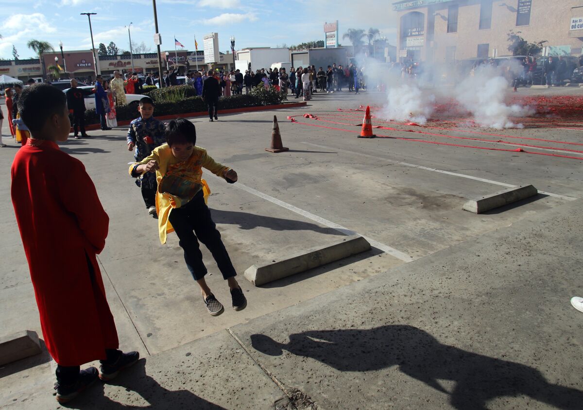 Kids jump out of the way as firecrackers are set off at the Westminster Tet Parade. 