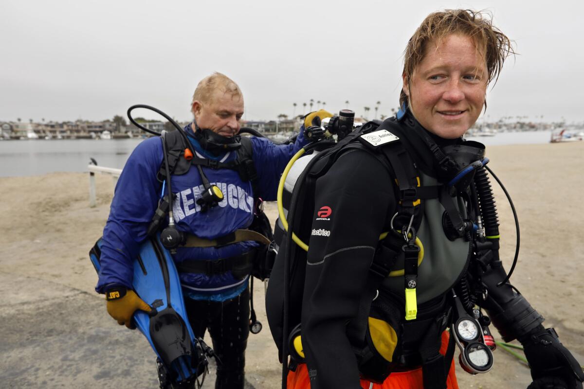 Ashley Arnold, right, gets rinsed off with a hose by Rog Hanson after a dive Alamitos Bay. (Carolyn Cole/Los Angeles Times)