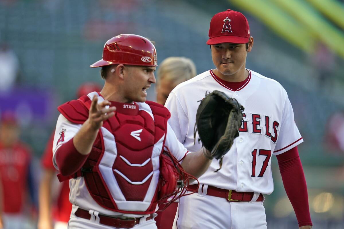 Angels catcher Max Stassi, left, talks to starting pitcher Shohei Ohtani before a game on Aug. 15, 2022.