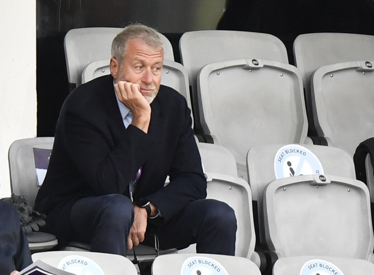 Chelsea soccer club owner Roman Abramovich sits alone in the stands with his hand holding his chin