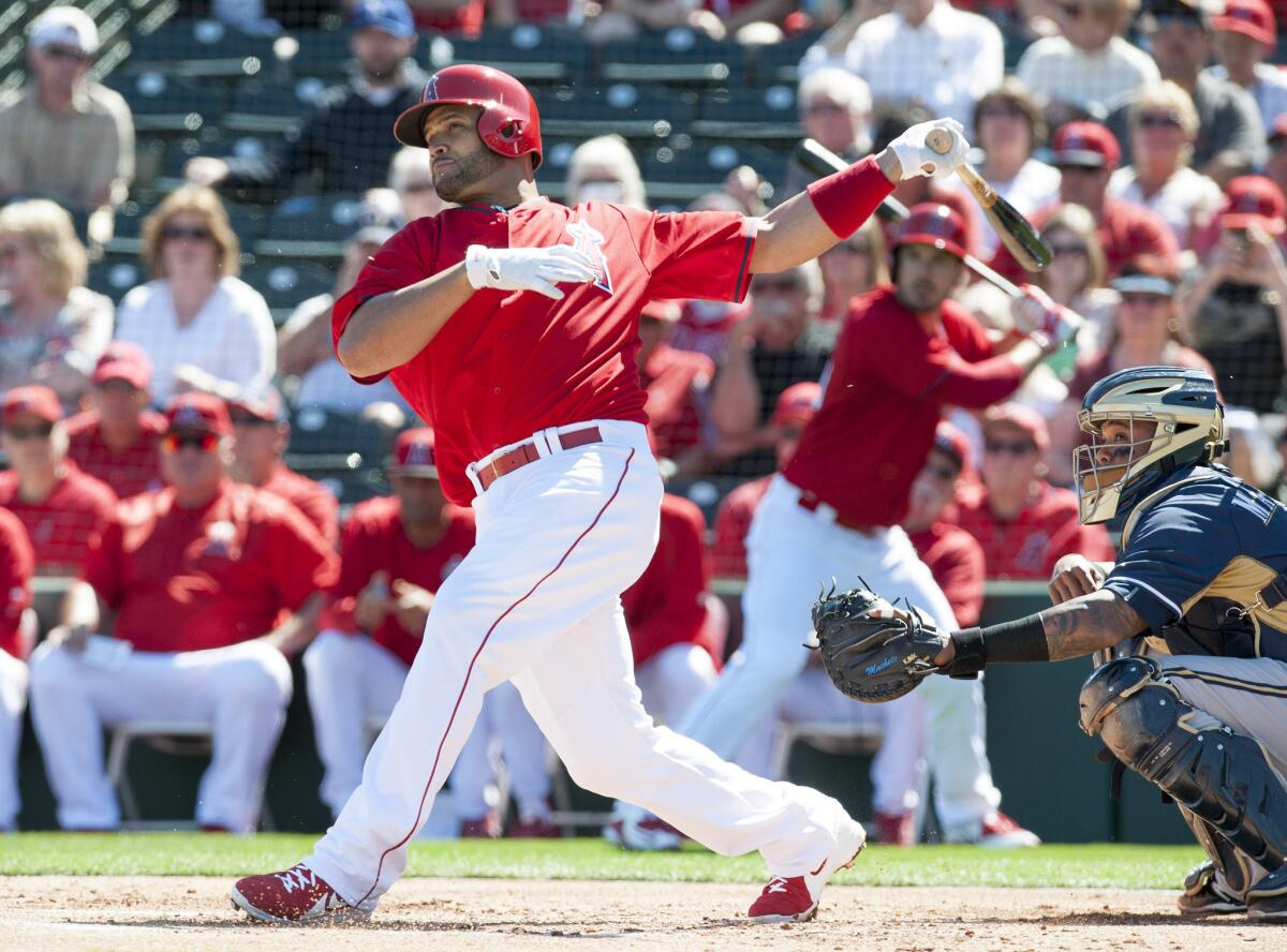 Angels first baseman Albert Pujols hits the ball against the Brewers during the Angels' spring training home opener.