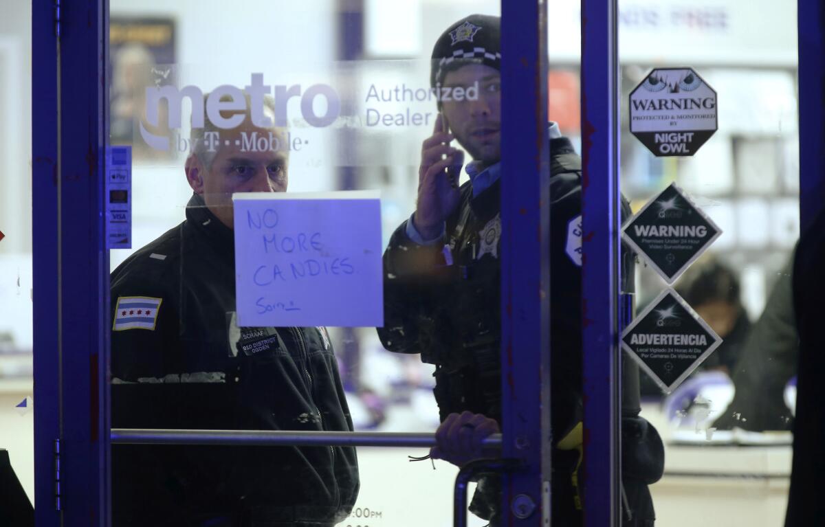 A police supervisor and officer stand inside a cellphone store where a 7-year-old girl was shot while trick-or-treating in Chicago on Thursday.