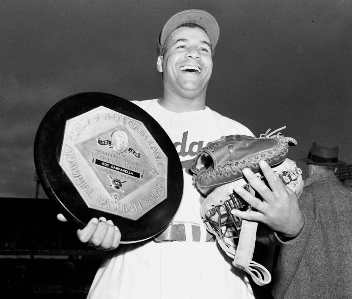 Brooklyn Dodger catcher Roy Campanella holds his gear and his National League 1951 Most Valuable Player award.