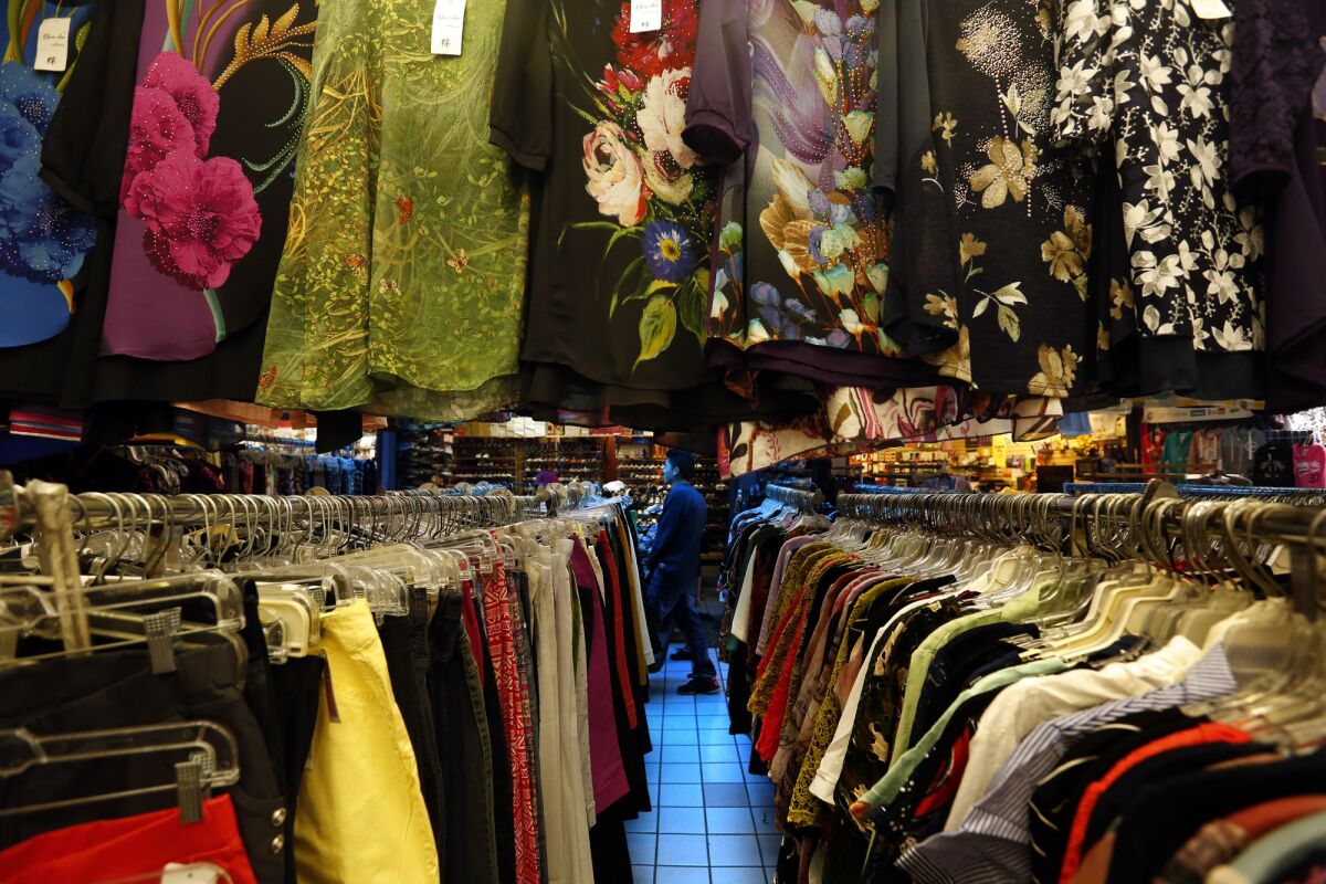 A shopper is framed by clothing for sale at the swap meets in Chinatown. (Genaro Molina / Los Angeles Times)