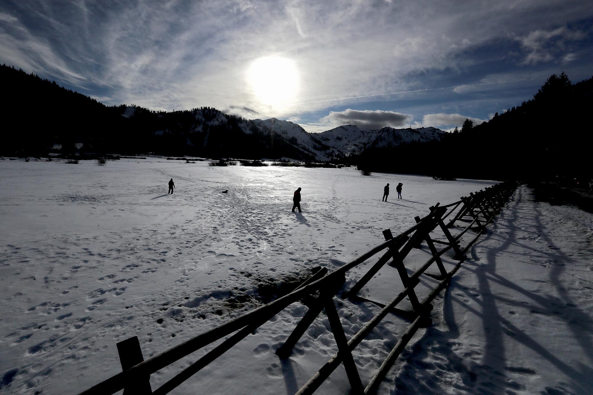 Visitors walk across a snow-covered meadow in Lake Tahoe.