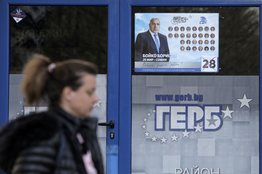 A woman passes by a poster depicting Bulgarian prime minister Boyko Borissov, in Sofia, Bulgaria, Wednesday, March 31, 2021. After months of nationwide anti-government protests over corruption, stalled reforms and a stagnating economy in the EU's poorest member state, Bulgarians are gearing up for a parliamentary election overshadowed by a deadly pandemic. (AP Photo/Valentina Petrova)