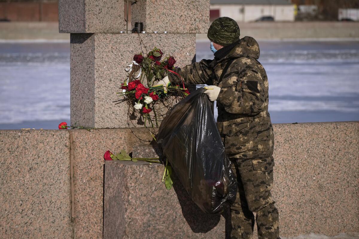 A worker removes flowers from a memorial.